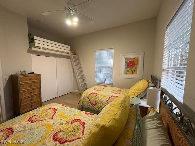 bedroom featuring multiple windows, a closet, ceiling fan, and light wood-type flooring