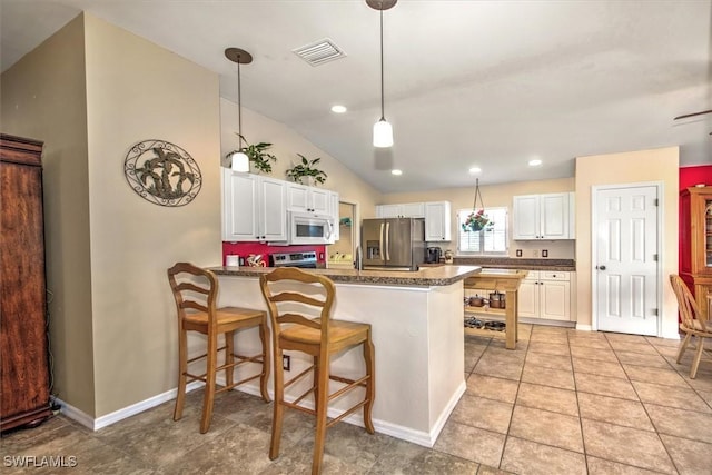 kitchen with stainless steel appliances, kitchen peninsula, hanging light fixtures, and white cabinets