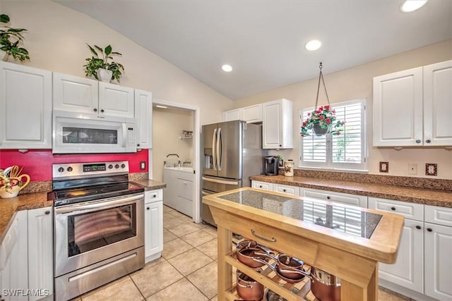 kitchen with washing machine and clothes dryer, vaulted ceiling, white cabinets, and appliances with stainless steel finishes