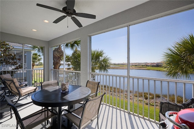 sunroom featuring a water view and ceiling fan