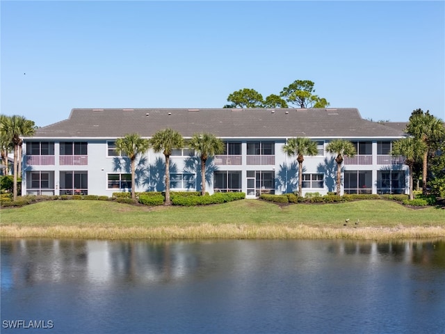 back of house with a water view and a lawn