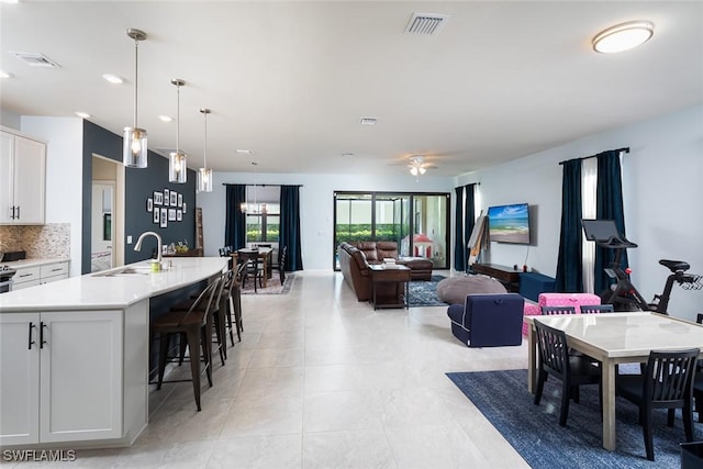 tiled dining room featuring sink and ceiling fan with notable chandelier