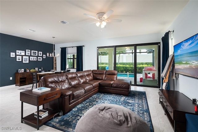 tiled living room with ceiling fan with notable chandelier