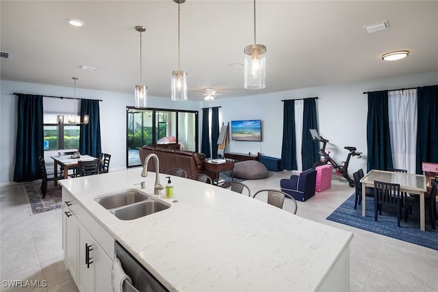 kitchen featuring pendant lighting, sink, a center island with sink, and white cabinets