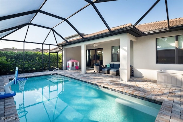 view of pool with ceiling fan, outdoor lounge area, glass enclosure, and a patio area