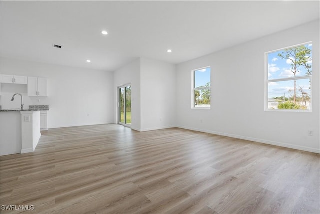 unfurnished living room with a healthy amount of sunlight and light wood-type flooring