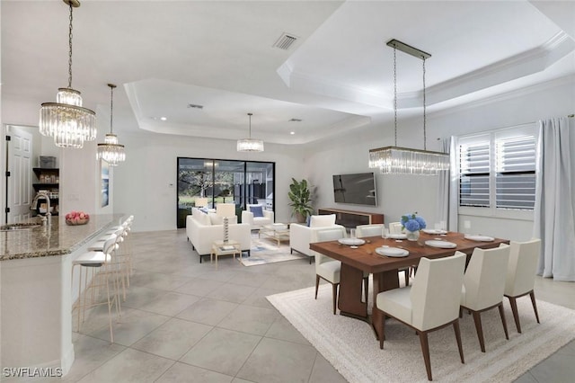 tiled dining room with an inviting chandelier, sink, ornamental molding, and a raised ceiling