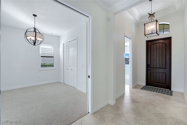 tiled entryway featuring ornamental molding and a chandelier