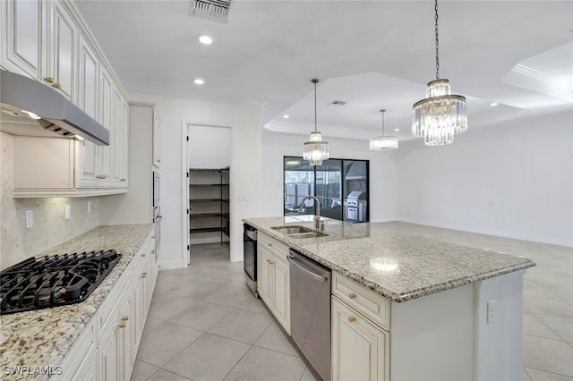 kitchen with sink, appliances with stainless steel finishes, a kitchen island with sink, decorative light fixtures, and a raised ceiling