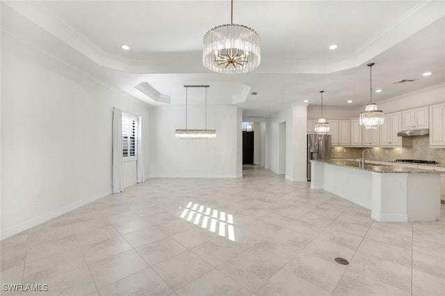 kitchen featuring a tray ceiling, pendant lighting, a chandelier, light stone counters, and stainless steel fridge with ice dispenser