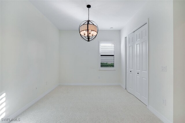 carpeted spare room featuring an inviting chandelier