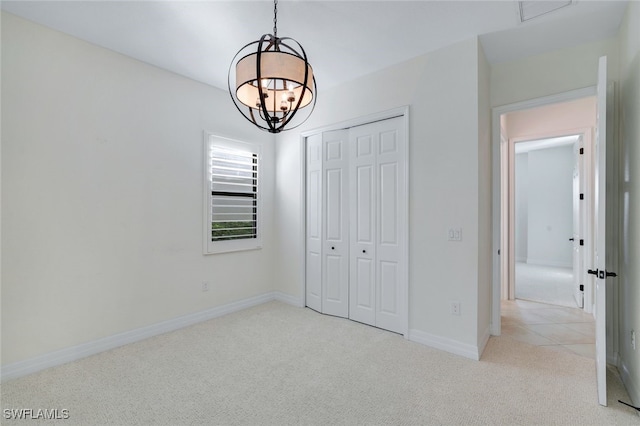 unfurnished bedroom with light carpet, a chandelier, and a closet