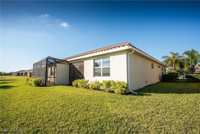 view of property exterior with glass enclosure and a lawn