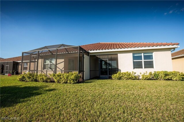 rear view of property featuring a lanai and a lawn