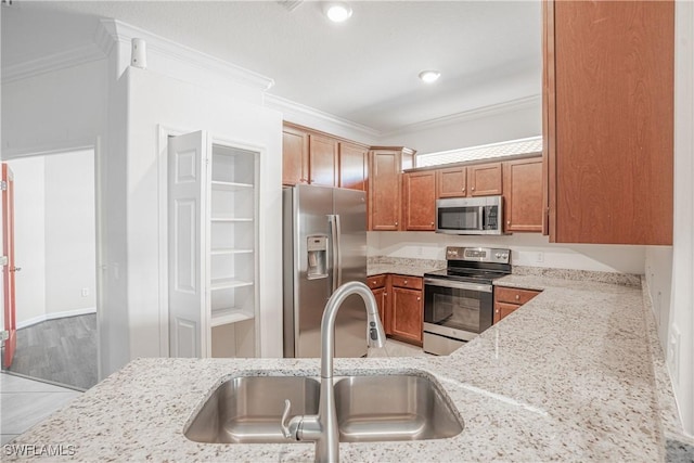 kitchen featuring light stone counters, stainless steel appliances, crown molding, and sink