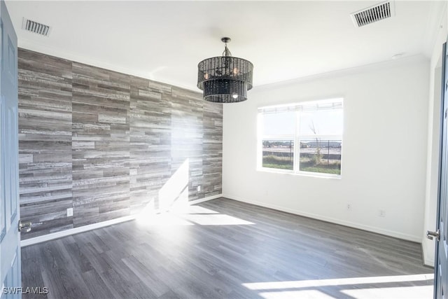 unfurnished dining area featuring dark hardwood / wood-style flooring, ornamental molding, and a chandelier