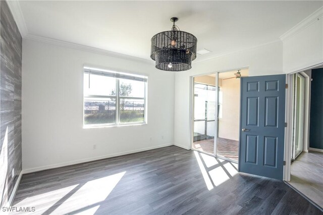 unfurnished room featuring dark hardwood / wood-style flooring, ornamental molding, and an inviting chandelier