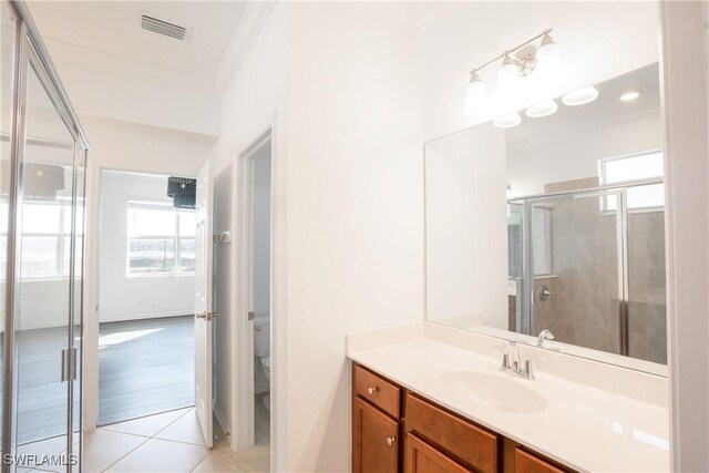 bathroom featuring a shower with shower door, tile patterned flooring, vanity, toilet, and crown molding