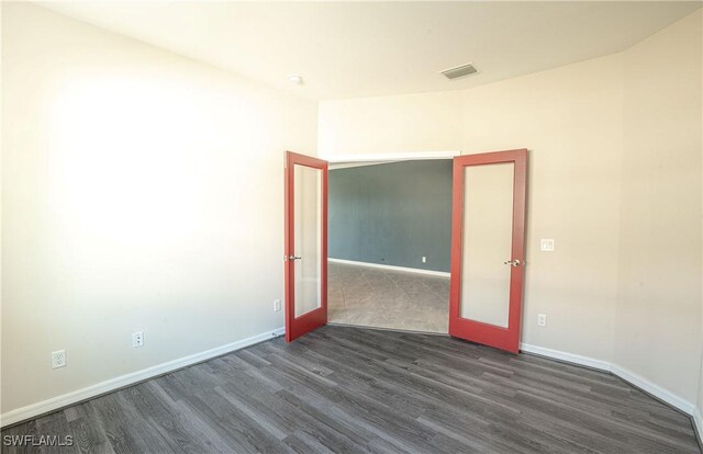 spare room featuring french doors and dark hardwood / wood-style flooring