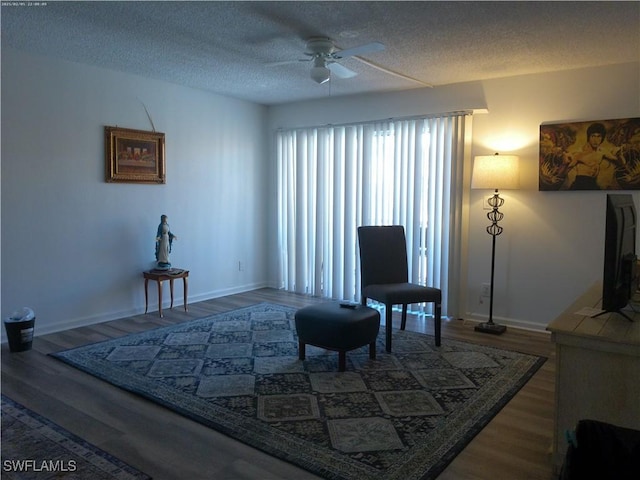 living area with ceiling fan, dark hardwood / wood-style floors, and a textured ceiling