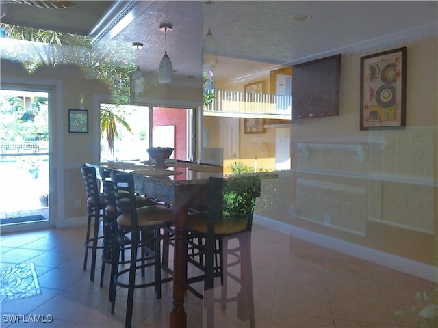 interior space featuring tile patterned flooring, pendant lighting, and a kitchen breakfast bar