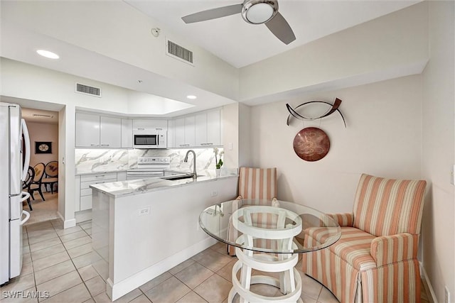 kitchen with sink, white appliances, white cabinetry, decorative backsplash, and kitchen peninsula