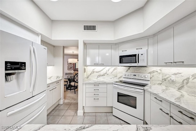 kitchen featuring light tile patterned flooring, white cabinetry, backsplash, light stone counters, and white appliances