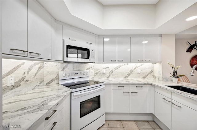 kitchen featuring white cabinetry, sink, light tile patterned floors, and white appliances