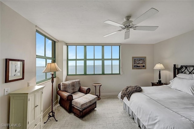 carpeted bedroom featuring multiple windows, ceiling fan, and a water view