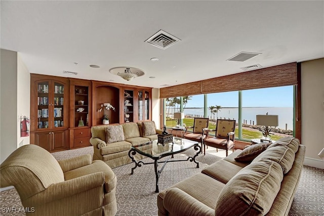 living room featuring light carpet, built in shelves, and a water view