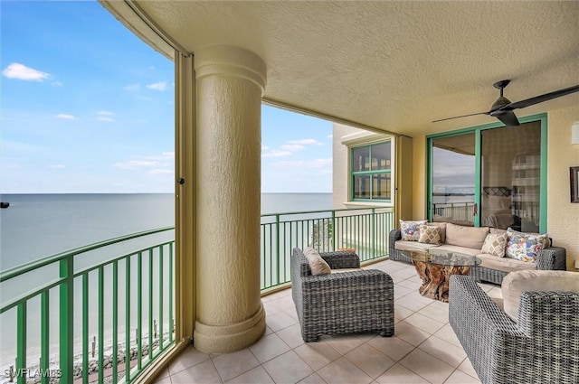 balcony featuring an outdoor living space, ceiling fan, and a water view