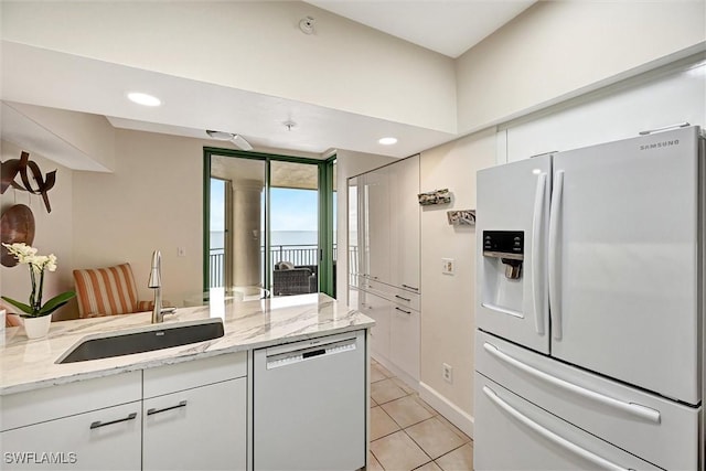 kitchen featuring dishwasher, sink, white cabinets, white refrigerator with ice dispenser, and light stone countertops