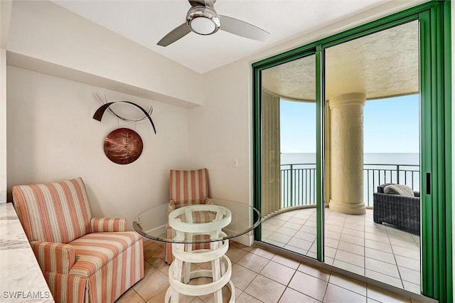 living area with a water view, ceiling fan, floor to ceiling windows, and light tile patterned flooring