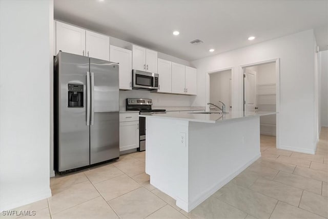 kitchen with appliances with stainless steel finishes, a center island with sink, and white cabinets