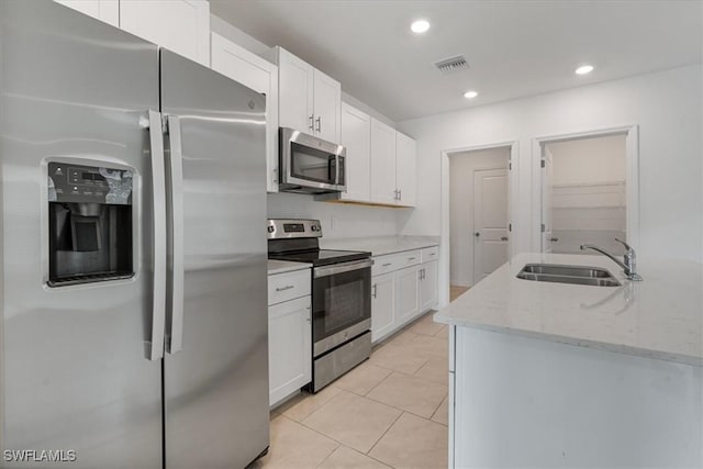 kitchen featuring sink, white cabinetry, stainless steel appliances, light stone countertops, and light tile patterned flooring