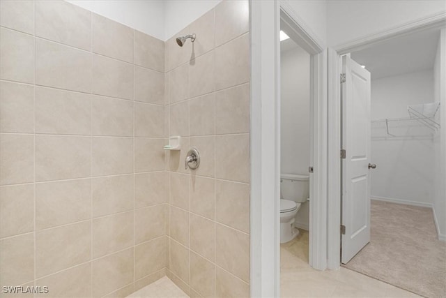 bathroom with tile patterned flooring, a tile shower, and toilet