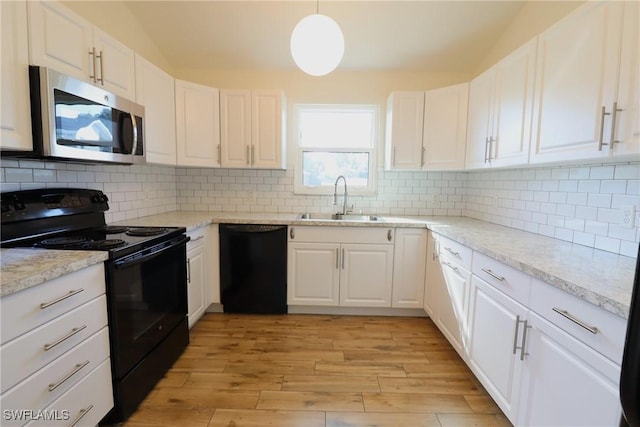 kitchen featuring sink, pendant lighting, white cabinets, and black appliances