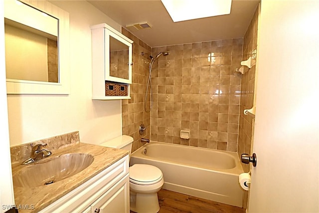 full bathroom with vanity, tiled shower / bath combo, wood-type flooring, and toilet