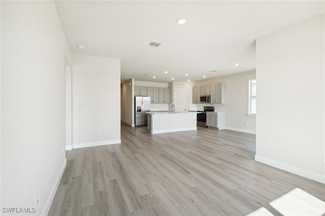 unfurnished living room featuring sink and light hardwood / wood-style flooring