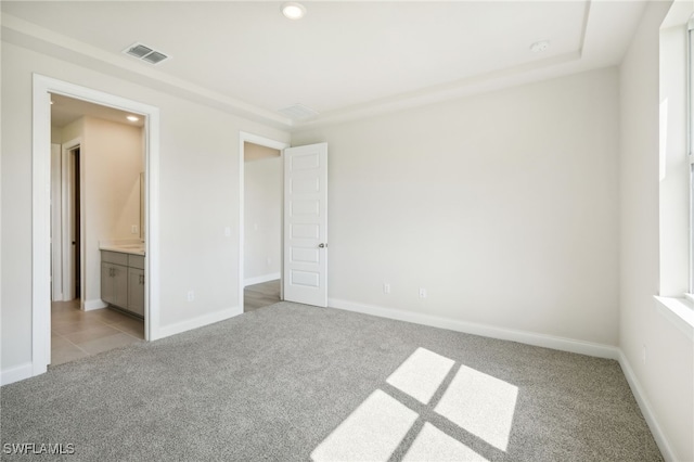 unfurnished bedroom featuring ensuite bath and light carpet