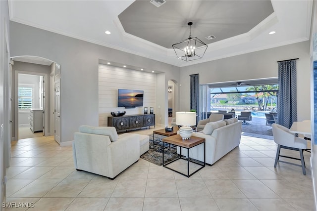 living room featuring crown molding, light tile patterned floors, an inviting chandelier, and a tray ceiling