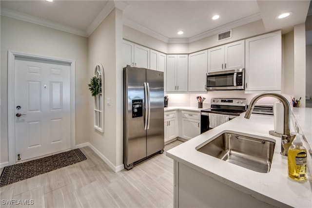 kitchen featuring white cabinetry, appliances with stainless steel finishes, sink, and ornamental molding