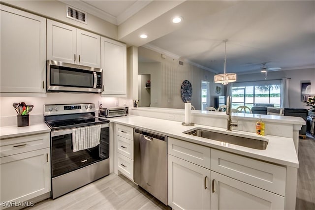 kitchen with sink, hanging light fixtures, stainless steel appliances, white cabinets, and kitchen peninsula