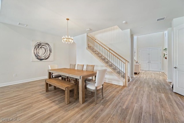 dining room featuring stairs, light wood finished floors, and visible vents