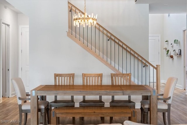 dining room featuring baseboards, stairs, a chandelier, and wood finished floors