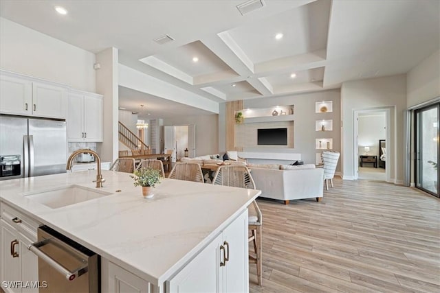 kitchen featuring coffered ceiling, a sink, visible vents, white cabinetry, and dishwasher