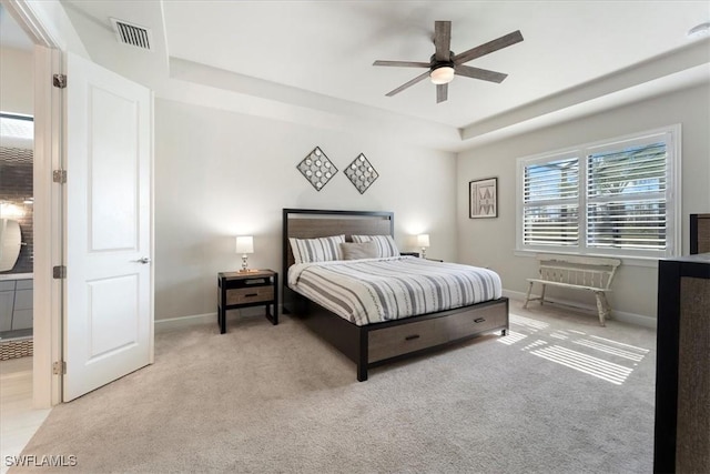 carpeted bedroom with a ceiling fan, a raised ceiling, visible vents, and baseboards