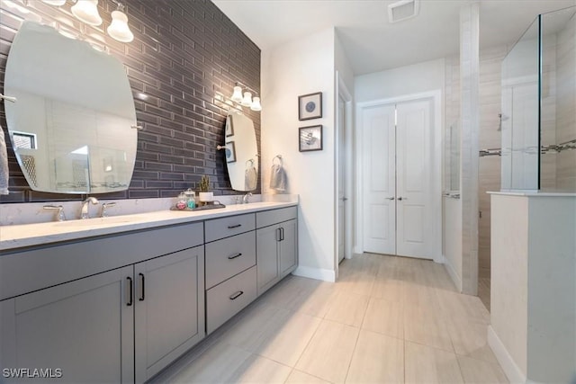 bathroom with visible vents, a sink, a tile shower, and double vanity