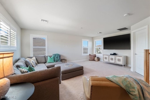 carpeted living area with visible vents, a wealth of natural light, and baseboards