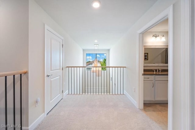 corridor featuring carpet flooring, a sink, and baseboards